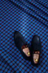 Male black leather shoes on dark blue checkered suit fabric background. Copy space for logo, design, advertising. Classic formal accessories for men