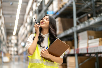 Asian warehouse staff woman checking inventory with clipboard in logistics management, working in...