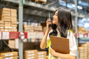 Asian warehouse staff woman checking inventory with clipboard in logistics management, working in...