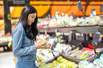 Portrait of beauty asian happy woman relax and enjoy shopping time with trolley cart buy healthy food package of grocery food with clean vegan eating vegetable and fruit at shopping supermarket