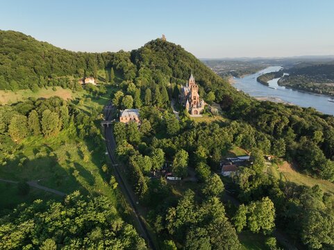 Weitlaeufige Panorama Luftaufnahme vom Drachenfels mit Schloss Drachenburg, Hirschburg, Petersberg und dem Rhein bei Koenigswinter im Siebengebirge an einem sonnigen Tag.