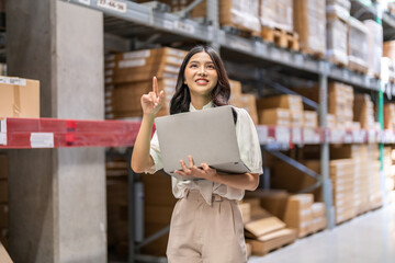 Female engineer is handling shipping and checking stock inventory in the warehouse with a laptop,...