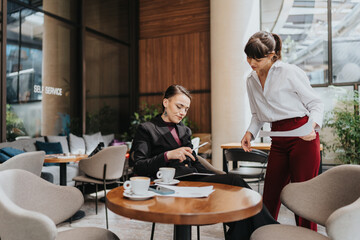 Professional women discussing work documents and strategies in a stylish cafe setting