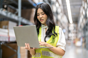 Female engineer is handling shipping and checking stock inventory in the warehouse with a laptop,...