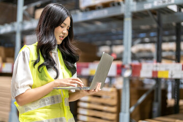 Female engineer is handling shipping and checking stock inventory in the warehouse with a laptop,...