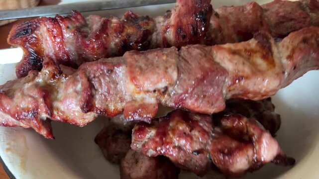roast meat on coals close-up. remove meat from skewers onto a plate shashlik