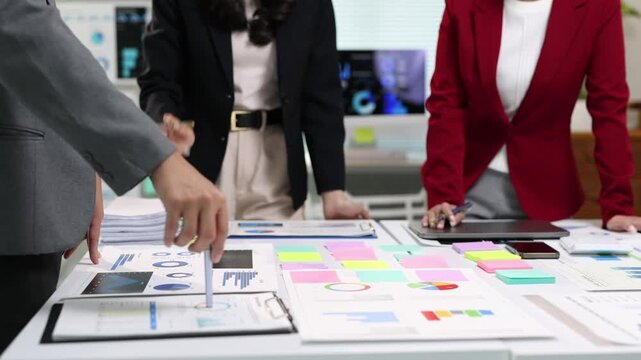 Professional business team collaborating while analyzing financial documents, using sticky notes during strategic meeting discussion. - Powered by Adobe