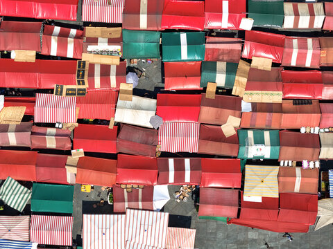 Aerial view of colorful market stalls create a vibrant mosaic across the Piazza della Repubblica, casting shadows in the Italian sun, Torino, Piemonte, Italy.