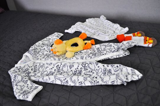 black and white baby clothes romper and rattle giraffe lying on the sofa