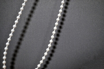 Minimalistic close-up of a beaded pull chain casting soft shadows on a textured fabric background....
