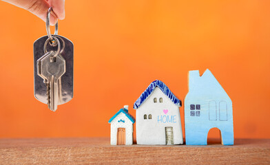 House key in girl hand with miniature house on orange background, property and real estate business...