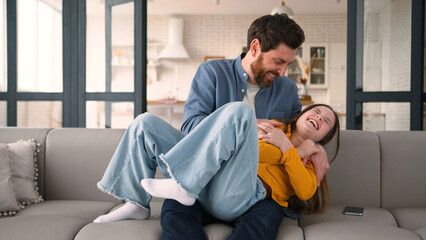 Caucasian man dad using mobile phone happy playful little daughter schoolgirl running father male...