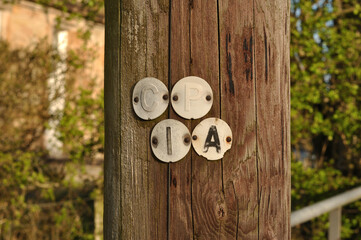 Metal Identification Labels Nailed to Old Timber Telegraph Pole in Close Up