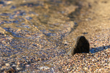 sea wave pattern on the shore and a little black rock in the sand for grafik and design purposes