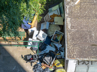 Aerial view of bulky waste and discarded furniture piled near a building. Urban cleanup or...
