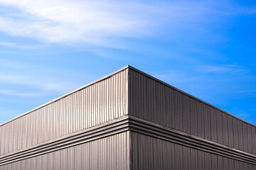 Fototapeta premium Warehouse industrial factory building with louver ventilation on black aluminium corrugated steel wall against blue sky background, Low angle and symmetric view