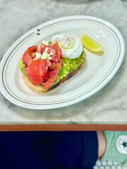 Avocado toast topped with juicy tomato slices and a perfectly poached egg — simple, nourishing, and always satisfying. Jakarta, Indonesia - June 18, 2025