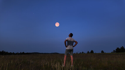 Amateur astronomer watching stars, Moon, planets and other celestial objects from a field in nature.