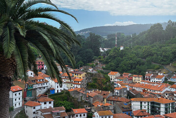 A picturesque view of a charming coastal village nestled into a hillside, with colorful traditional houses cascading down towards a tranquil harbor. Cudillero, Spain