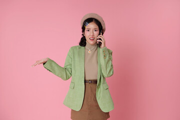 young Asian woman confused and gestures open hand phone call suggesting a challenging conversation or misunderstanding isolated on pink background.