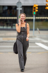 Full body portrait of a woman walking and laughing while talking with mobile phone