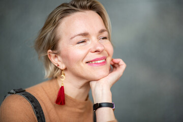 Close-up portrait of a smiling woman resting her chin on her hand, looking serene and content
