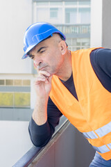 Portrait of an engineer wearing protective workwear posing looking at an unspecified point leaning chin on hand