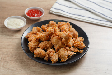 Crispy Popcorn Chicken with sauce and mayonnaise on a black plate. Perfect for recipes, articles or any cooking content.