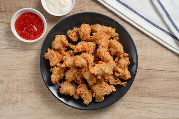 Crispy Popcorn Chicken with sauce and mayonnaise on a black plate. Perfect for recipes, articles or any cooking content.