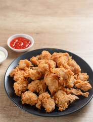 Crispy Popcorn Chicken with sauce and mayonnaise on a black plate. Perfect for recipes, articles or any cooking content.