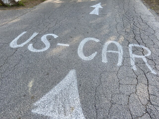 Weathered road with us car arrow signs on cracked pavement
