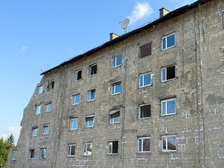 Dilapidated building exterior with weathered walls and satellite dish under clear sky