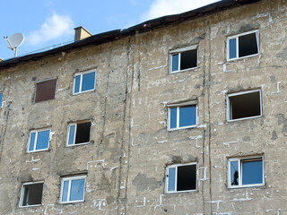Urban renovation: old apartment building with missing windows under construction