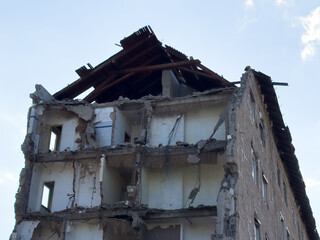 Partially collapsed concrete building with exposed floors and damaged roof