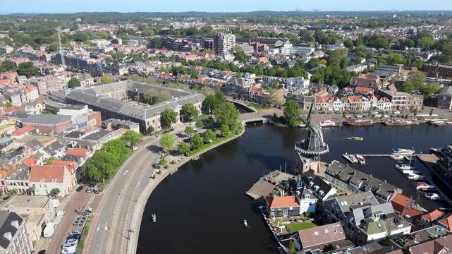 Aerial view of the historic De Adriaan windmill standing tall on the Spaarne river, surrounded by boats and buildings, Haarlem, North Holland, Netherlands.