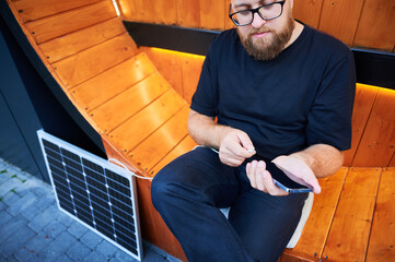 Cropped view of man connecting smartphone to photovoltaic solar panel. Integration of sustainable...