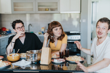 A group of friends engaging in lively conversation and sharing a meal in a bright kitchen. They...