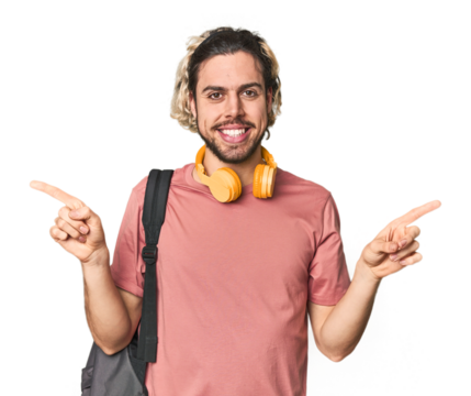 Young student with backpack and headphones pointing to different copy spaces, choosing one of them, showing with finger.