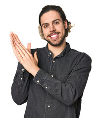 Young Caucasian man in studio setting feeling energetic and comfortable, rubbing hands confident.