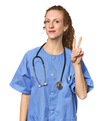 Redhead young caucasian  nurse in studio showing number two with fingers.