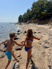 Boy and girl running and playing on a wild beach during a hot summer day. Joyful childhood moment full of freedom, energy, and outdoor fun by the sea.