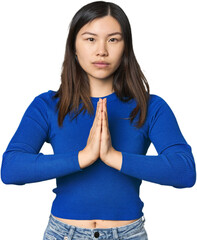 Young Chinese woman praying, showing devotion, religious person looking for divine inspiration.