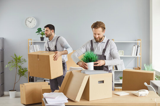 Packing boxes, moving delivery pack service, male movers team moving cardboard boxes, loading, unloading setting up, new house stuff, carrying stacks of cardboard relocation boxes in office room