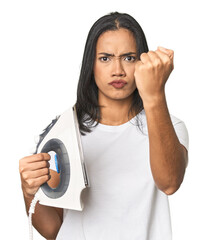 Latina with iron, studio setup showing fist to camera, aggressive facial expression.