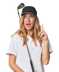 Young blonde golfer in studio pointing upside with opened mouth.