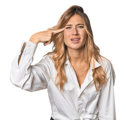 Caucasian blonde woman in studio showing a disappointment gesture with forefinger.