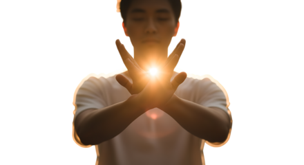 Man with eyes closed, hands forming an 'X' with bright golden light emanating from between palms, symbolizing energy and focus.