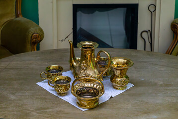 Collection of old oil lamps arranged on a windowsill. Metal reflectors visible in the background, retro-style interior.