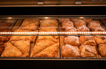 Fresh sweet pastries and puff triangles in bakery showcase for breakfast