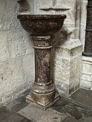 Ancient holy water font carved in polished stone